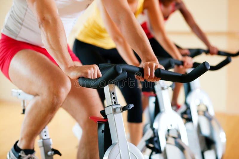 Three people spinning in the gym, exercising for their legs and cardio training, only limbs and wheels to be seen. Three people spinning in the gym, exercising for their legs and cardio training, only limbs and wheels to be seen