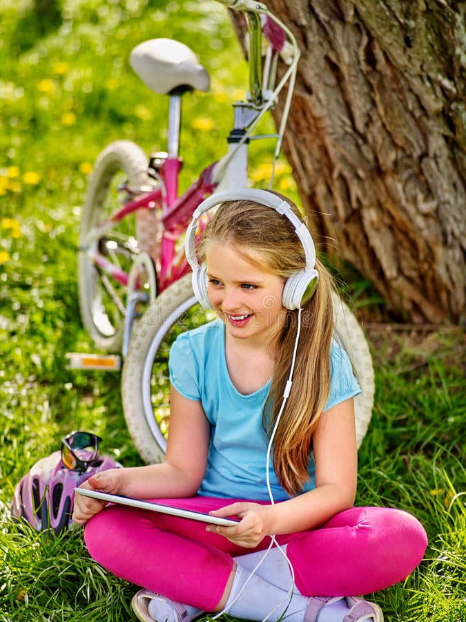Bicycle шлемофон девушки нося наблюдая на ПК таблетки стоковое изображение Bicycle шлемофон девушки нося наблюдая на ПК таблетки стоковое изображение