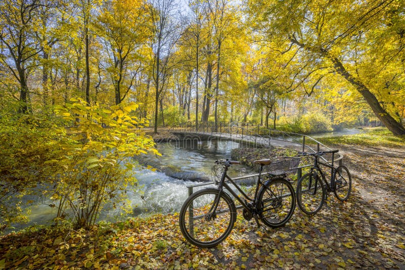 Bicycles at a small bridge over a creek in the park English Garden in autumn, Munich, Germany