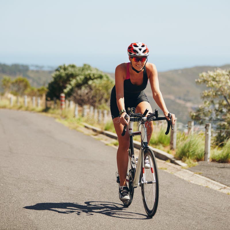Bicyclette d'équitation de jeune femme sur la route ouverte photo stock Bicyclette d'équitation de jeune femme sur la route ouverte photo stock