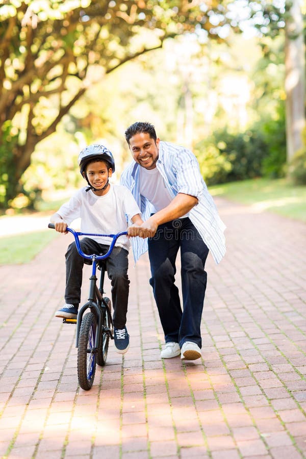 Bicyclette de enseignement de fils de père photos stock Bicyclette de enseignement de fils de père photos stock