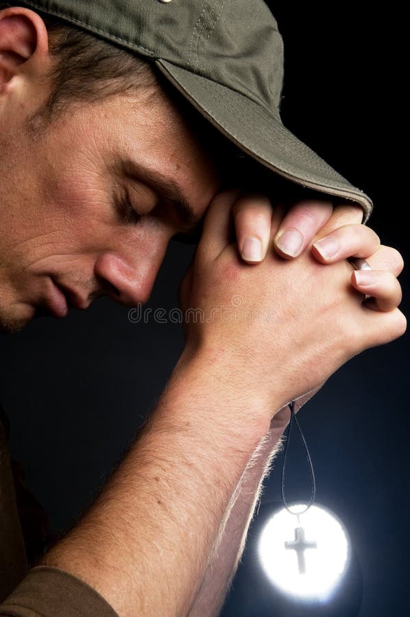 Praying man holding a cross in front of a bright light. Praying man holding a cross in front of a bright light.