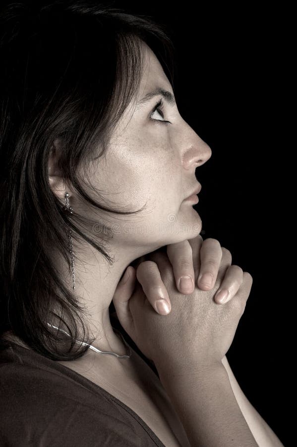 Low key portrait of a young woman praying in the dark. Low key portrait of a young woman praying in the dark