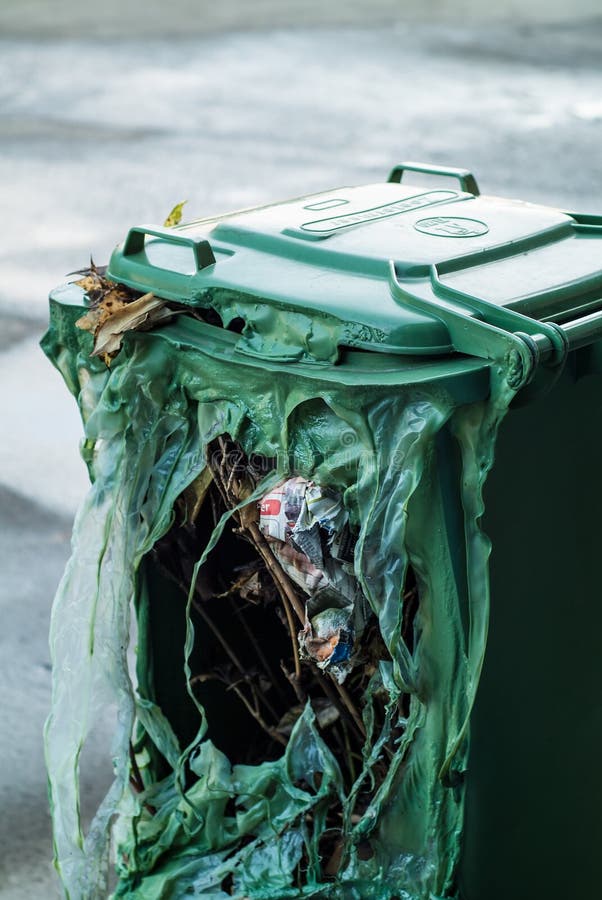 Green garbage can burnt by vandalists with large hole in it. Green garbage can burnt by vandalists with large hole in it