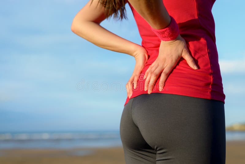 Female athlete lower back painful injury. Caucasian fitness girl gripping her lowerback because sport injury after exercising and running. Female athlete lower back painful injury. Caucasian fitness girl gripping her lowerback because sport injury after exercising and running.