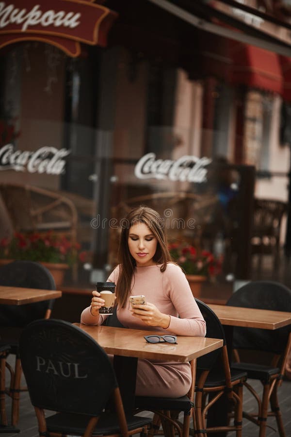 09 12 2019, Bielorussia, Minsk: Ritratto estivo di una giovane donna vestita di beige che beve un caffè in un bar Paul fotografia stock libera da diritti 09 12 2019, Bielorussia, Minsk: Ritratto estivo di una giovane donna vestita di beige che beve un caffè in un bar Paul fotografia stock libera da diritti