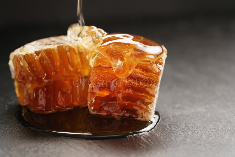 Bienenhonig gießt über Bienenwabe auf Schieferbrett lizenzfreies stockfoto Bienenhonig gießt über Bienenwabe auf Schieferbrett lizenzfreies stockfoto