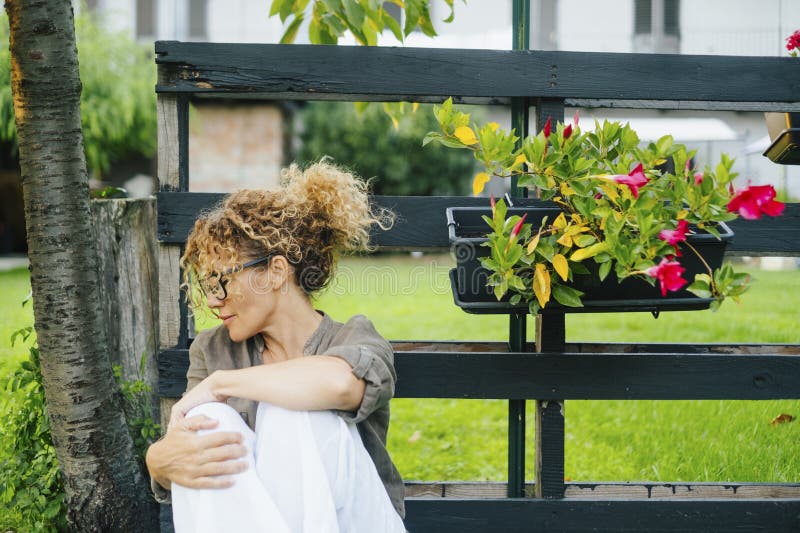 One lady outside home enjoy time and rela in green garden. Wellbeing and nature feeling people. Sadness. One lady outside home enjoy time and rela in green garden. Wellbeing and nature feeling people. Sadness