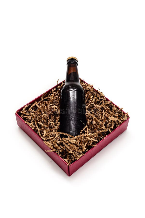 A Beer bottle in a red box full of shredded brown paper for a gift. A Beer bottle in a red box full of shredded brown paper for a gift.