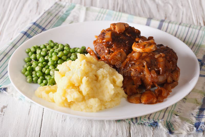 Bife de Salisbúria com batatas e close-up das ervilhas verdes em uma placa fotografia de stock Bife de Salisbúria com batatas e close-up das ervilhas verdes em uma placa fotografia de stock