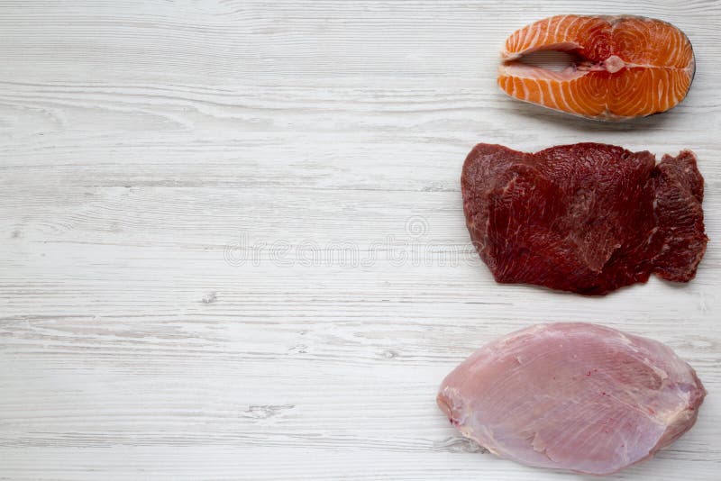 Bife salmon cru cru, carne da carne e peito de peru no fundo de madeira branco, vista superior Configuração lisa imagens de stock Bife salmon cru cru, carne da carne e peito de peru no fundo de madeira branco, vista superior Configuração lisa imagens de stock