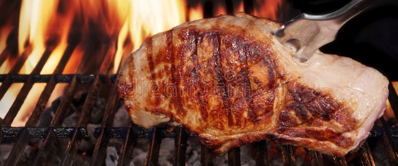 Biff för grisköttfransyska på varmt flammande grillfestgaller med gaffeln