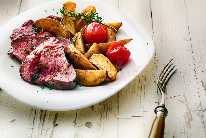 Bifteck de boeuf de rôti avec les cales et la tomate de pomme de terre photos libres de droits Bifteck de boeuf de rôti avec les cales et la tomate de pomme de terre photos libres de droits
