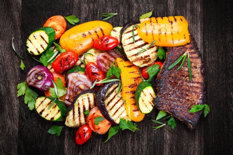 Bifteck de boeuf et légumes grillés À la coupure du fond foncé de conseil photo stock Bifteck de boeuf et légumes grillés À la coupure du fond foncé de conseil photo stock