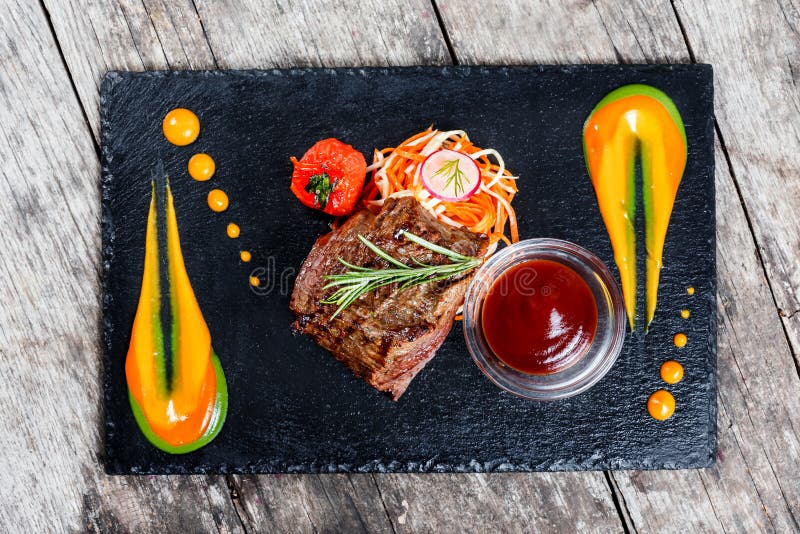 Bifteck de boeuf grillé avec de la salade fraîche et la sauce à BBQ sur le fond en pierre d'ardoise sur la fin en bois de fond P image stock Bifteck de boeuf grillé avec de la salade fraîche et la sauce à BBQ sur le fond en pierre d'ardoise sur la fin en bois de fond P image stock
