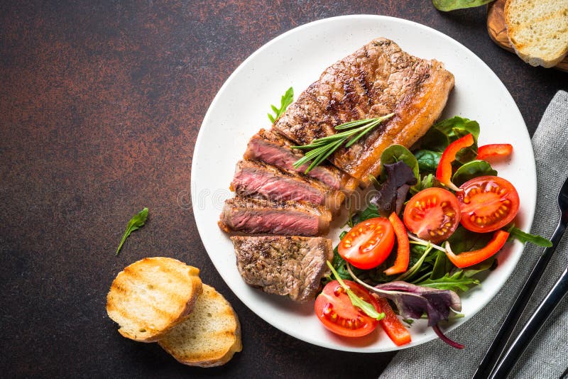 Bifteck grillé de striploin de boeuf avec la vue supérieure de salade fraîche photographie stock Bifteck grillé de striploin de boeuf avec la vue supérieure de salade fraîche photographie stock