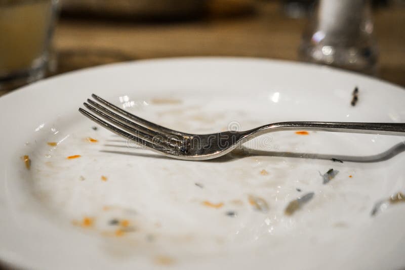 Bifurcación en una placa después de una comida Placa sucia con los rastros de comida en la tabla fotografía de archivo libre de regalías Bifurcación en una placa después de una comida Placa sucia con los rastros de comida en la tabla fotografía de archivo libre de regalías