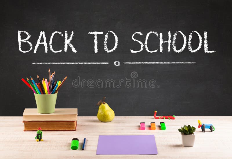 Back to school concept with writing on blackboard in capital letters and a desk with papers, fruit. Back to school concept with writing on blackboard in capital letters and a desk with papers, fruit