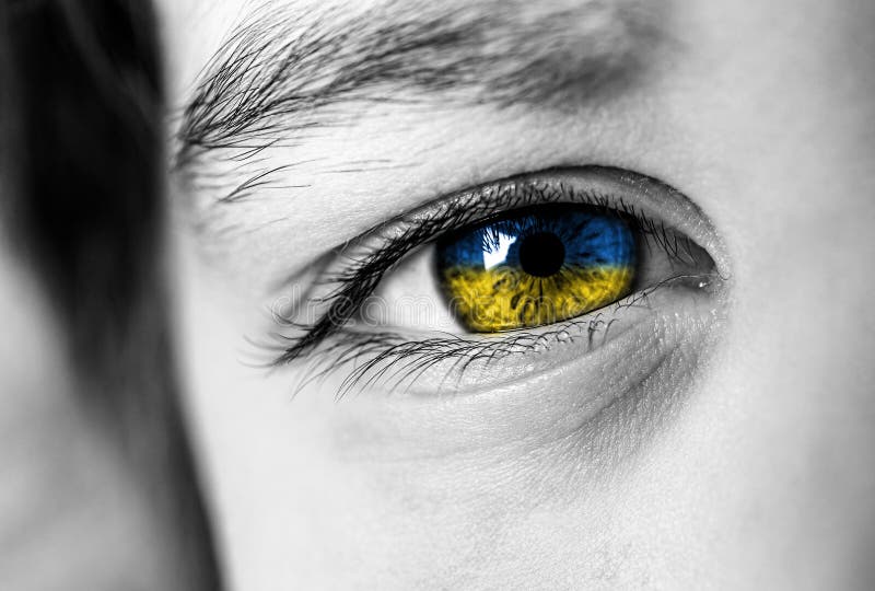 Big beautiful eye close-up. Blue and yellow colors iris. Concept of war in Ukraine. Caucasian appearance. Emotional stress. Pain