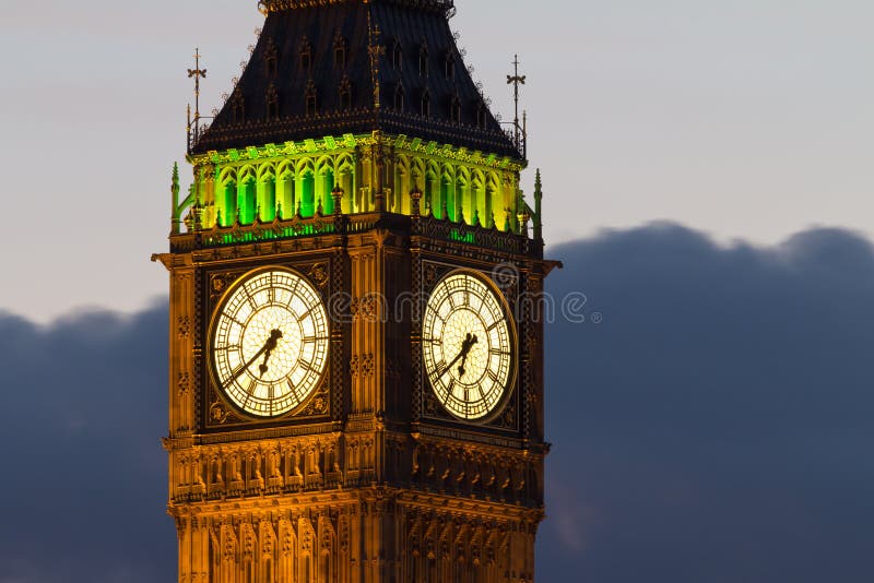 A fragment of the famous tower of Big Ben. The tower officially called the Elizabeth Tower. Close-up of the clock dials with night illumination of the building. Evening. London, UK. A fragment of the famous tower of Big Ben. The tower officially called the Elizabeth Tower. Close-up of the clock dials with night illumination of the building. Evening. London, UK.