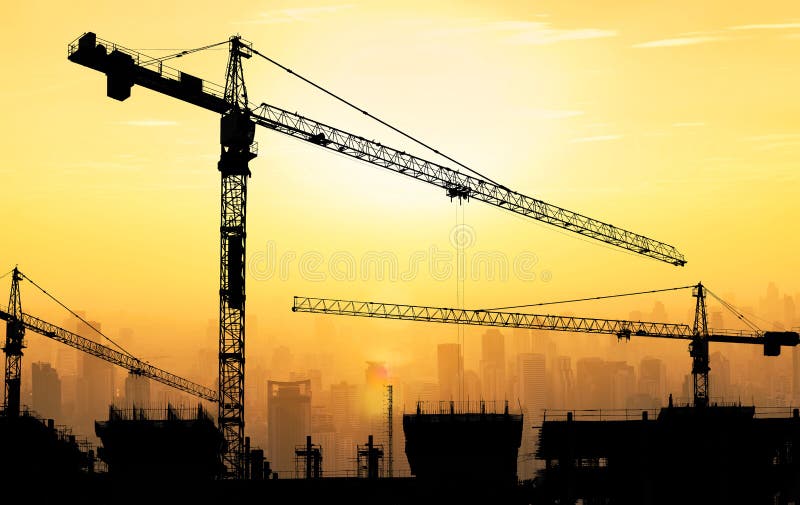 Big cranes and building construction against beautiful dusky sun