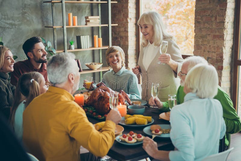 Big family happy thanksgiving gathering sit table pensioner woman hold champagne glass toast to small little kids people