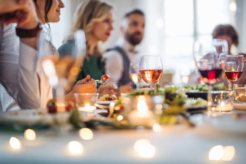 A big family sitting at a table on a indoor birthday party, eating.