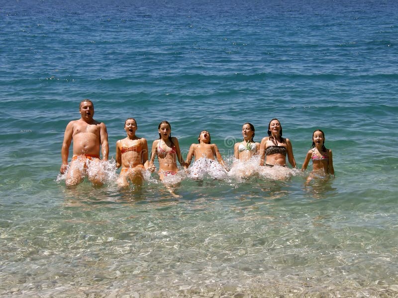 Mother, father, children s (relatives) bath on vacation at sunny day in Adriatic sea - Croatia (Dalmatia). They are arranged in line and hold hands and jump into the sea. Horizontal color photo. Mother, father, children s (relatives) bath on vacation at sunny day in Adriatic sea - Croatia (Dalmatia). They are arranged in line and hold hands and jump into the sea. Horizontal color photo.