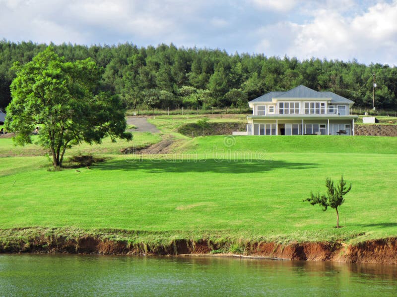 Big house with lawn next to lake