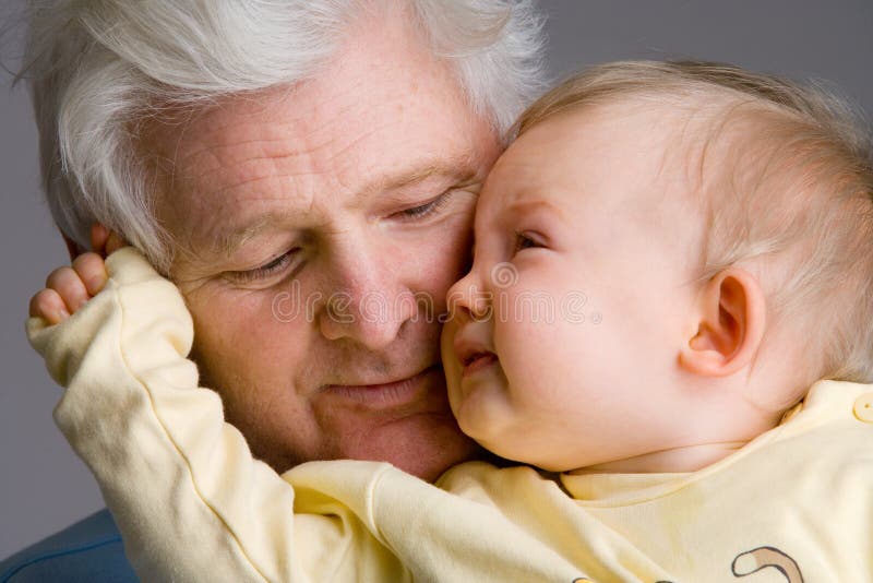 Cute little baby ragazza che indossa una maglietta gialla è abbracciare suo nonno.