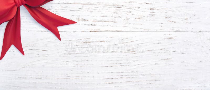 Big isolated red ribbon on a wooden surface with copy space. Suitable for Christmas cards and banners. Concept of celebration or