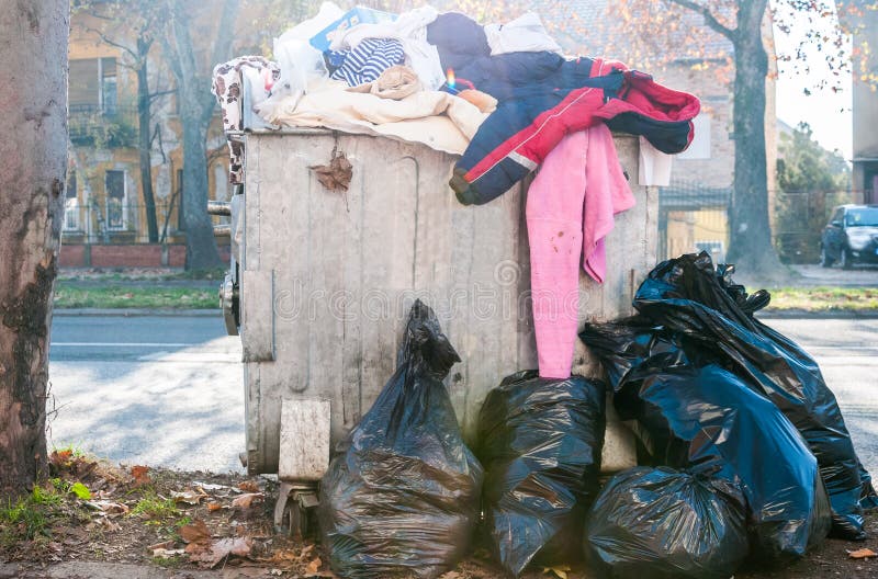 Big two metal dumpster garbage cans full of overflow litter and junk  polluting the street in the city Stock Photo