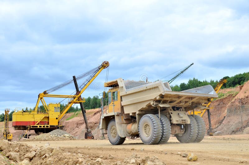 Big mining truck amid huge excavators in an open-pit dolomite quarry. Loading and transportation of stone ore in a limestone stock images