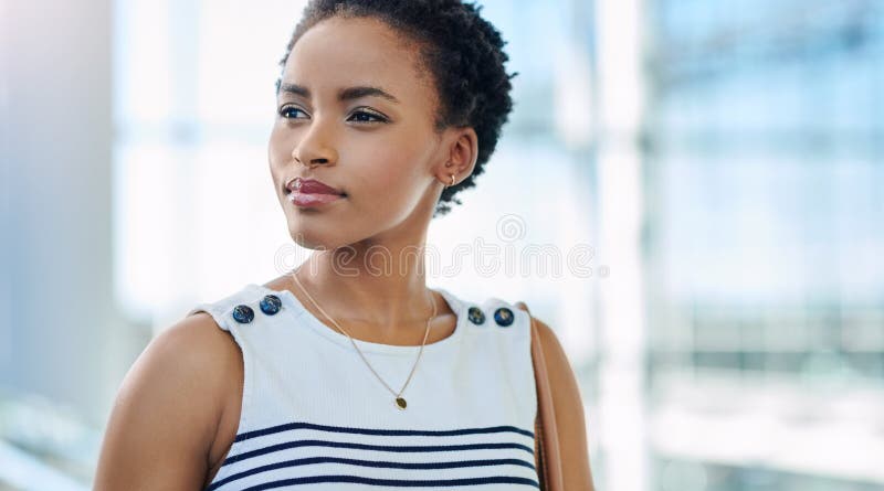 Big plans in that beautiful mind. an attractive young businesswoman looking thoughtful while standing in a modern office