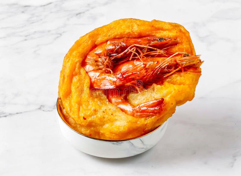 Big Prawn Fritters con corteza crujiente servidos en una pequeña taquilla aislada en un fondo de mármol con vistas a la comida de singapur