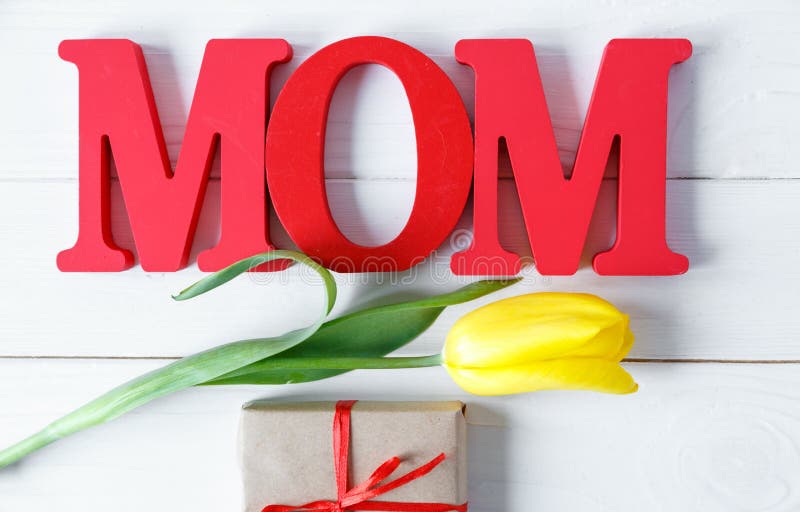 Big red letters Mom lies on the table with gift card and yellow tulips. Flowers for gift. Mother`s day concept. royalty free stock photography Big red letters Mom lies on the table with gift card and yellow tulips. Flowers for gift. Mother`s day concept. royalty free stock photography