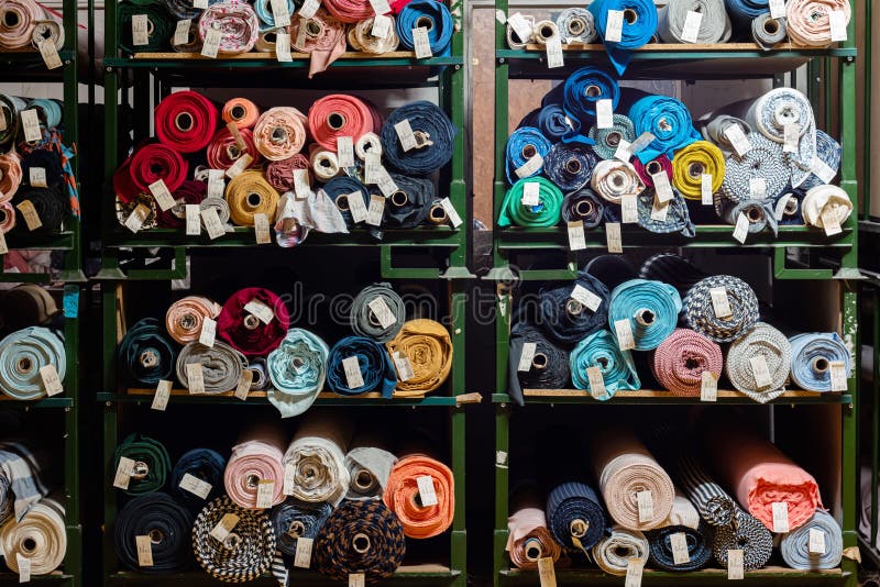 Big rolls of colorful fabric stacked on factory shelves ready for production