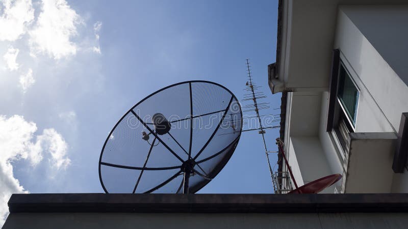Big Satellite Dish, small red Satellite Dish and Antenna TV on the roof of house against with blue sky and white clouds royalty free stock images Big Satellite Dish, small red Satellite Dish and Antenna TV on the roof of house against with blue sky and white clouds royalty free stock images