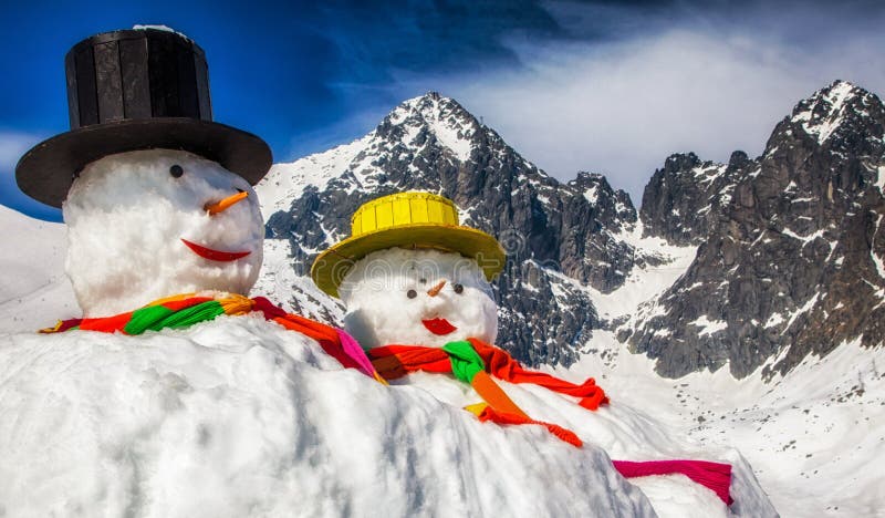 Big snowmans in winter snowy country. Peak Lomnicky stit in High Tatras mountains in Slovakia at background