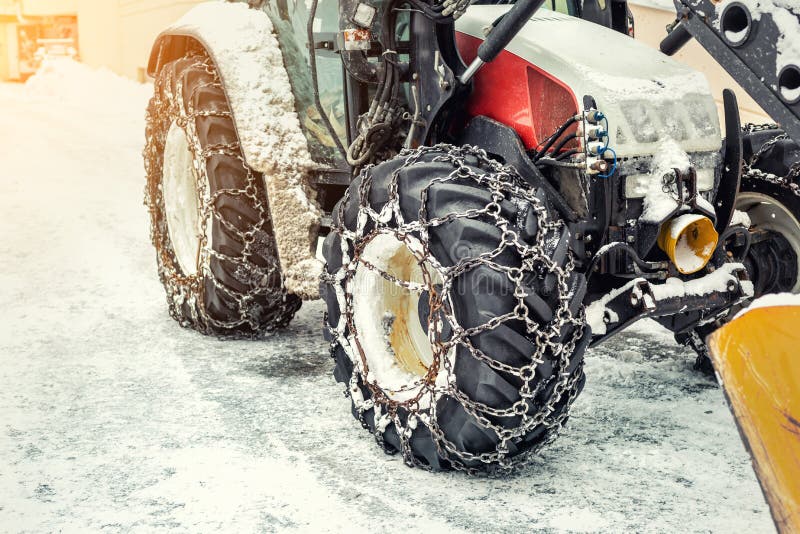 Big tractor machine with steel metal chains driving through slippery icy road or city street at alpine mountain region in winter royalty free stock image Big tractor machine with steel metal chains driving through slippery icy road or city street at alpine mountain region in winter royalty free stock image
