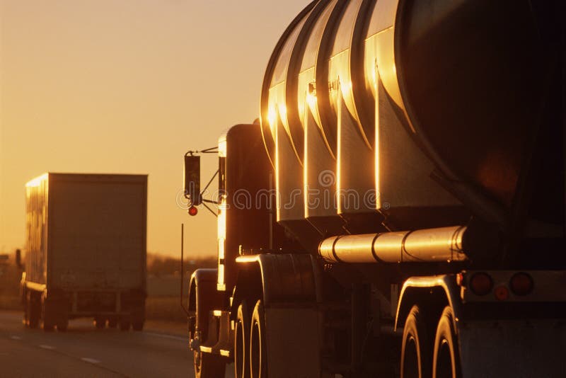 Big trucks driving. Big rig trucks on the highway at sunset Big trucks driving. Big rig trucks on the highway at sunset