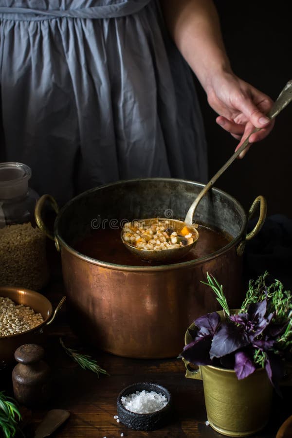 Big vintage copper pan with soup and ladle in female hand