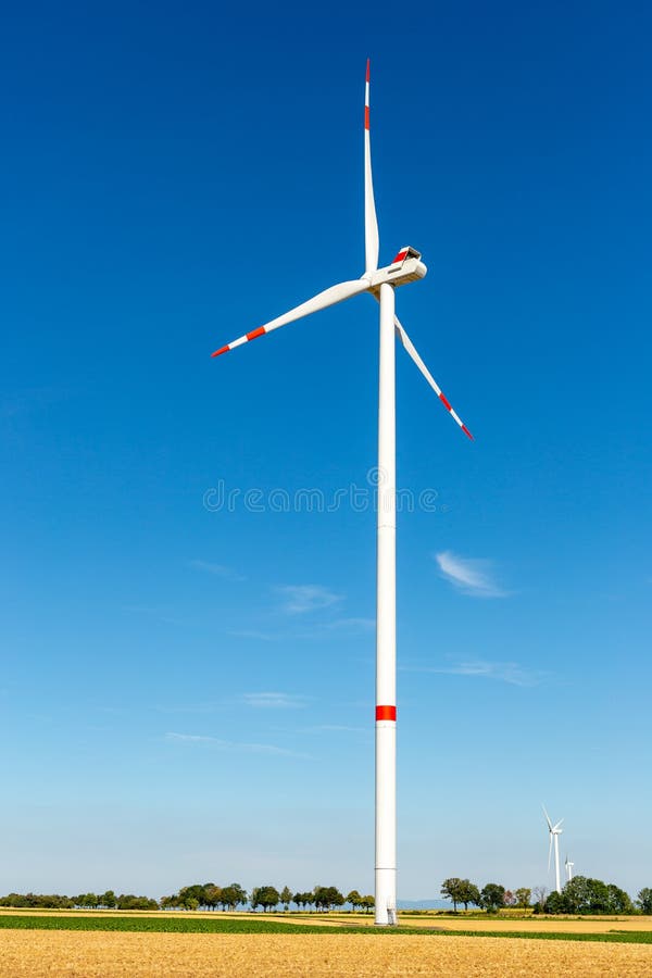 Big white wind turbine with trees