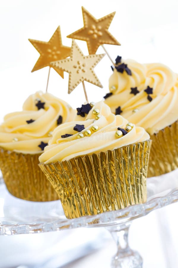 Three golden cupcakes on a glass cake stand. Three golden cupcakes on a glass cake stand