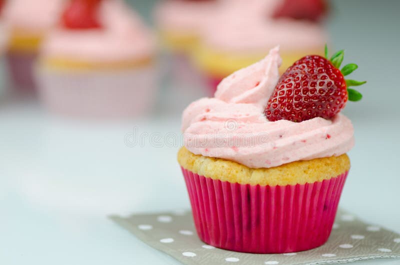 Bigné rosa delizioso della fragola con una fragola Bigné e glassa rosa con fragole sulla cima fotografia stock Bigné rosa delizioso della fragola con una fragola Bigné e glassa rosa con fragole sulla cima fotografia stock