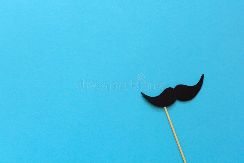 Paper mustache on booth props on blue paper background. Cut out style. Movember concept. Top view. Flat lay. Copy space. Paper mustache on booth props on blue paper background. Cut out style. Movember concept. Top view. Flat lay. Copy space