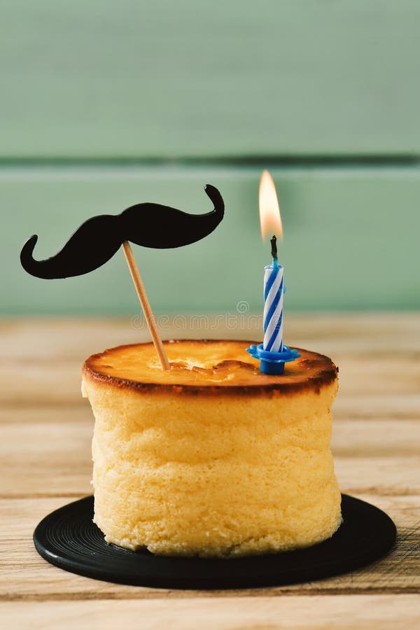 Bigote y vela encendida en un pastel de queso imagenes de archivo Bigote y vela encendida en un pastel de queso imagenes de archivo
