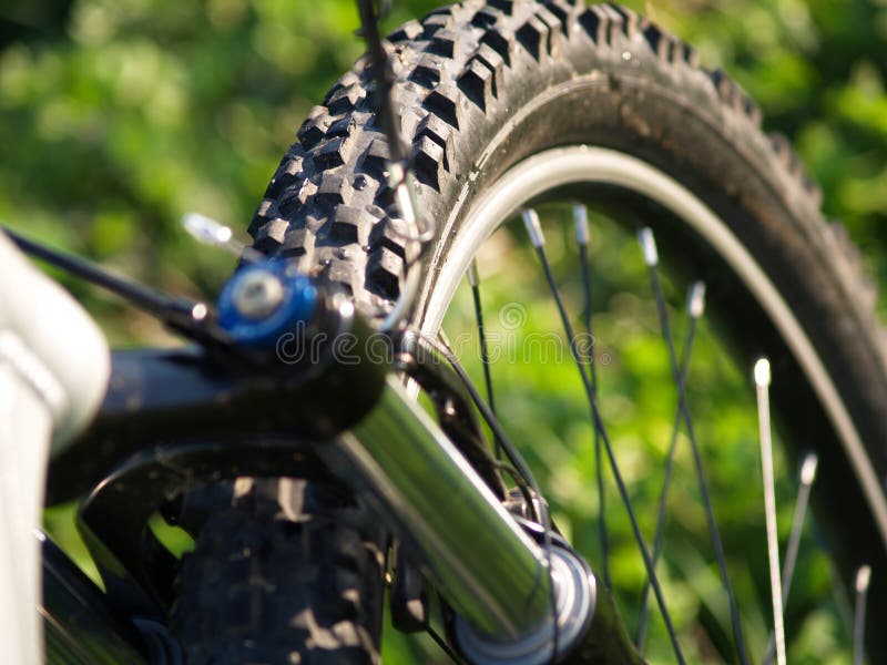 The front part of a bike showing the tire and suspension front fork. The front part of a bike showing the tire and suspension front fork