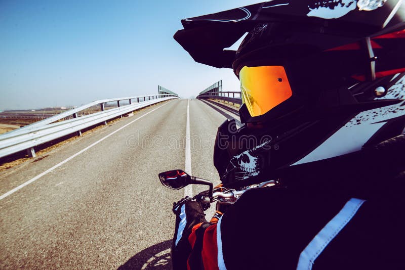 Biker in action looking rear on the road toned with a trendy filter stock image