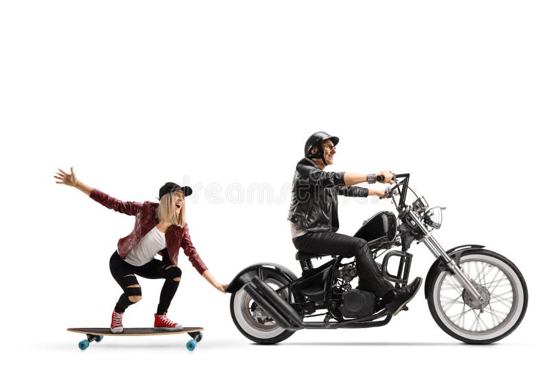 Biker on a chopper pulling a young woman on a skateboard